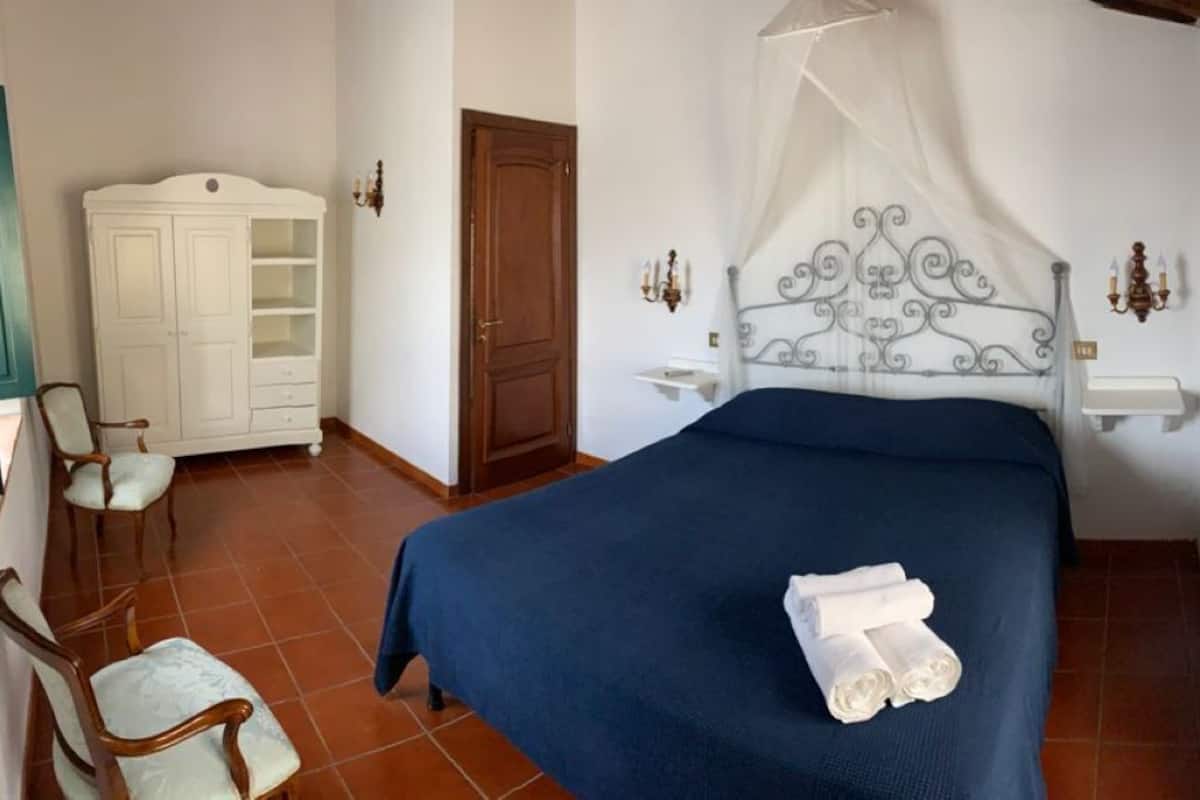 Un dormitorio con cama, armario, silla y mesita de noche.