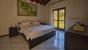 Ein Schlafzimmer mit einem großen Bett, einem Nachttisch, einem Schreibtisch, einem Fenster mit Vorhängen und einem Wandbild.