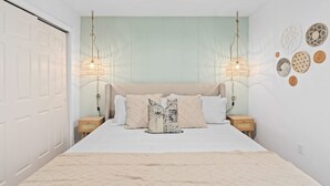 Ein Schlafzimmer mit einem Bett, zwei Nachttischen, einem Deckenventilator und Wanddekoration.