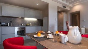 A modern kitchen with a dining area, featuring a table set for breakfast with orange juice, a croissant, and a pitcher. - Borgo di Drugolo Apartment n.9 (Drugolo)