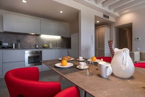A modern kitchen with a dining area, featuring a table set for breakfast with orange juice, a croissant, and a pitcher. - Borgo di Drugolo Apartment n.9 (Drugolo)