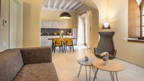 Una sala de estar moderna con un sofá, dos mesitas auxiliares y una zona de comedor con sillas amarillas.