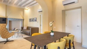 Una sala de estar moderna con comedor, que incluye un sofá, una silla, una mesa y una chimenea.