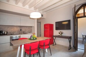 Eine moderne Küche mit weißen Schränken, einem roten Kühlschrank und einem Essbereich mit roten Stühlen.