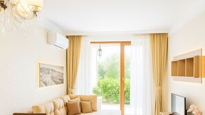 Una sala de estar moderna con sofá, mesa de comedor, televisor y un amplio ventanal con cortinas.