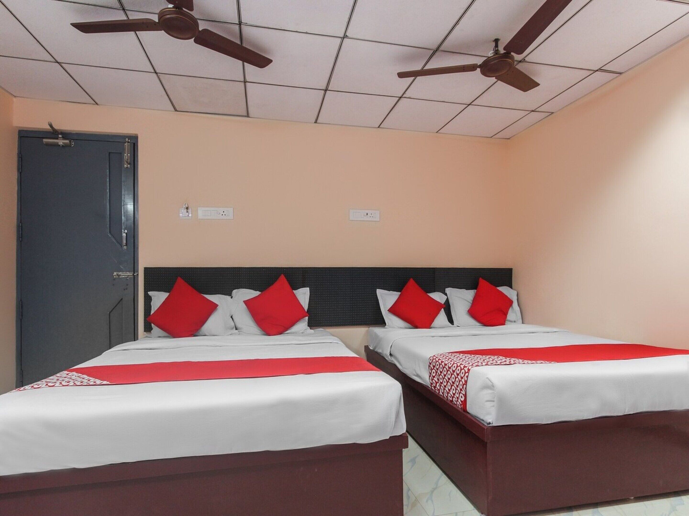 A hotel room with two beds, each with red and white bedding, and a ceiling fan.