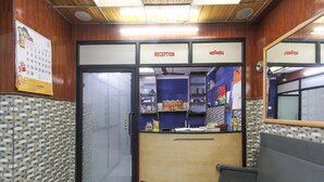 Un espace d’accueil comprenant un comptoir de réception, une porte à pousser et un banc.