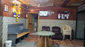 Une pièce avec un plafond en bois, une table ronde, un banc et plusieurs chaises.