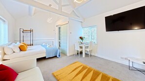 A modern, well-lit room with a bed, a sofa, a dining area, and a TV. - The Saddlery  -  a cottage that sleeps 2 guests  in 1 bedroom (Bridlington)