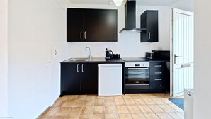 A compact kitchen with black cabinets, a dishwasher, a stove, and a sink. - The Saddlery  -  a cottage that sleeps 2 guests  in 1 bedroom (Bridlington)