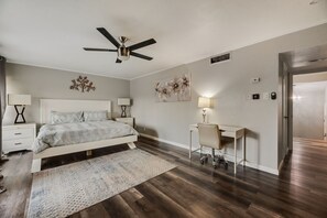 Ein Schlafzimmer mit Bett, Schreibtisch, Stuhl und Deckenventilator.