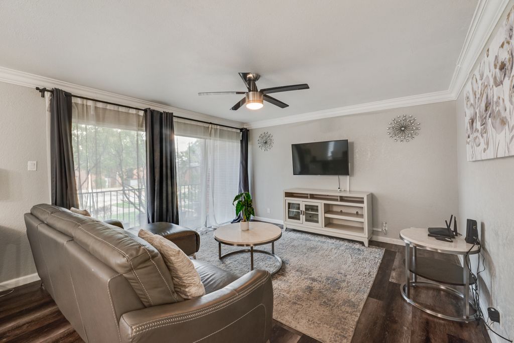 A living room with a sofa, a coffee table, a TV, and a ceiling fan.