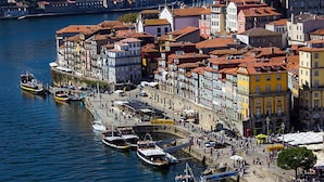 A waterfront area with colorful buildings, a stone wall, and boats docked along the river. - T2 Matosinhos Sul | Beach 5min | Metro Door | Internet | 6Pax (Matosinhos)