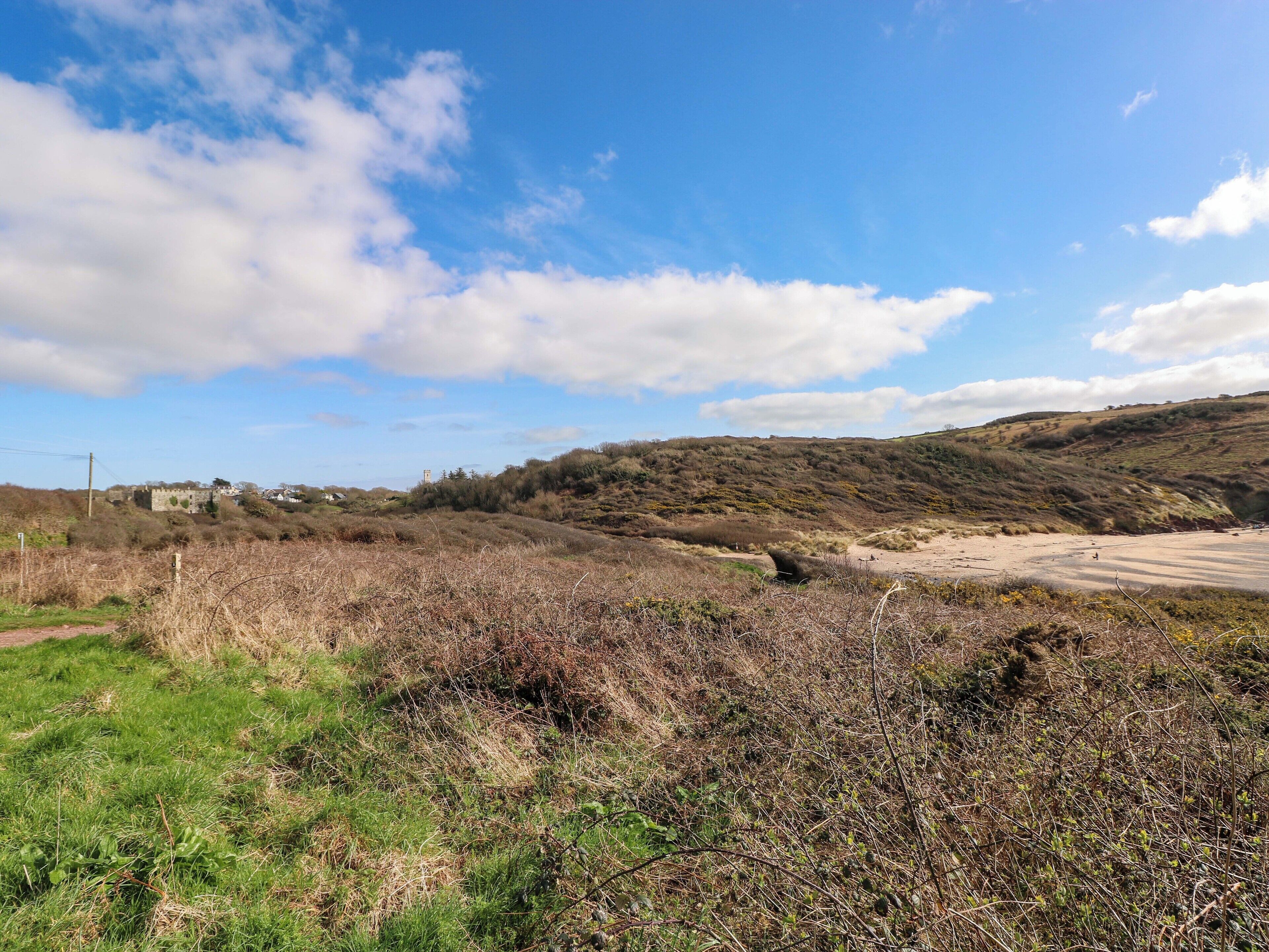 Un paysage rural avec une colline, une route et un bâtiment visible au loin.