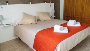 A neatly made bed with beige bedding and a red blanket, a bedside table with a lamp, and a wooden wardrobe in the background. - Apartment in the center of Padrón 2 (Padrón)