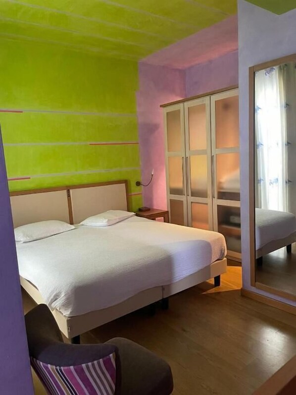 A bedroom with a bed, a nightstand, a wardrobe, and a chair. - Appartamenti Porta Nuova 80 (Verona)