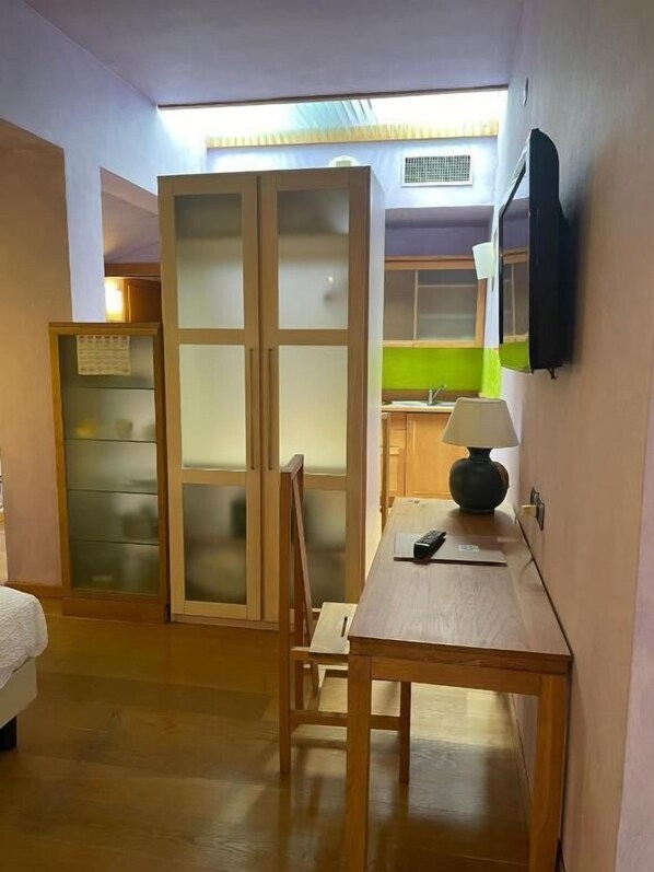 A room with a wooden table, a chair, a bed, and a sliding door with frosted glass panels. - Appartamenti Porta Nuova 80 (Verona)