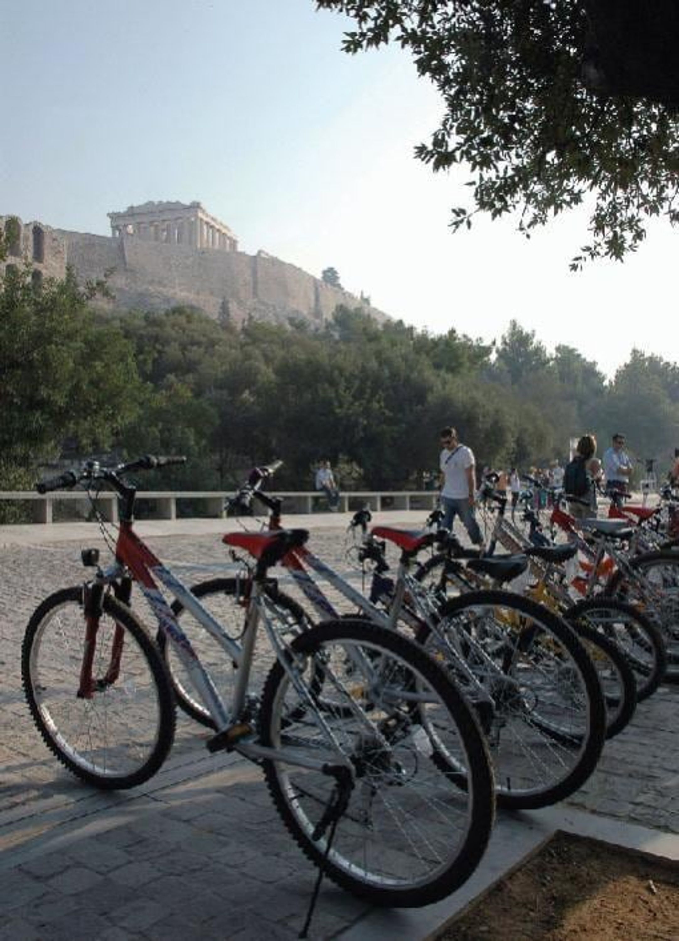 Bicicletas estacionadas en un área pavimentada, con un edificio histórico al fondo.