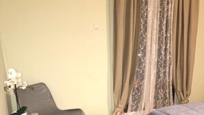 Un dormitorio con cama, una silla, una mesita y un tapete a rayas.