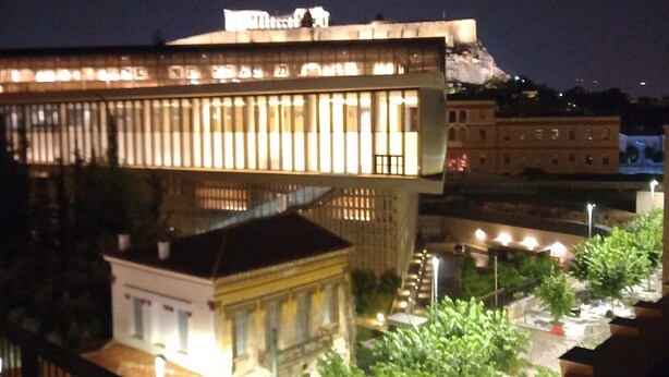 Vista nocturna de un edificio con diseño arquitectónico moderno, que destaca por una estructura en su azotea.