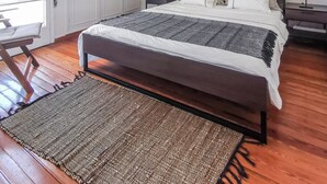 Un dormitorio con una cama grande, piso de madera, una lámpara en el techo y vistas al exterior.