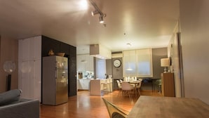 Una cocina moderna con refrigerador, comedor con sillas y una mesa de madera.