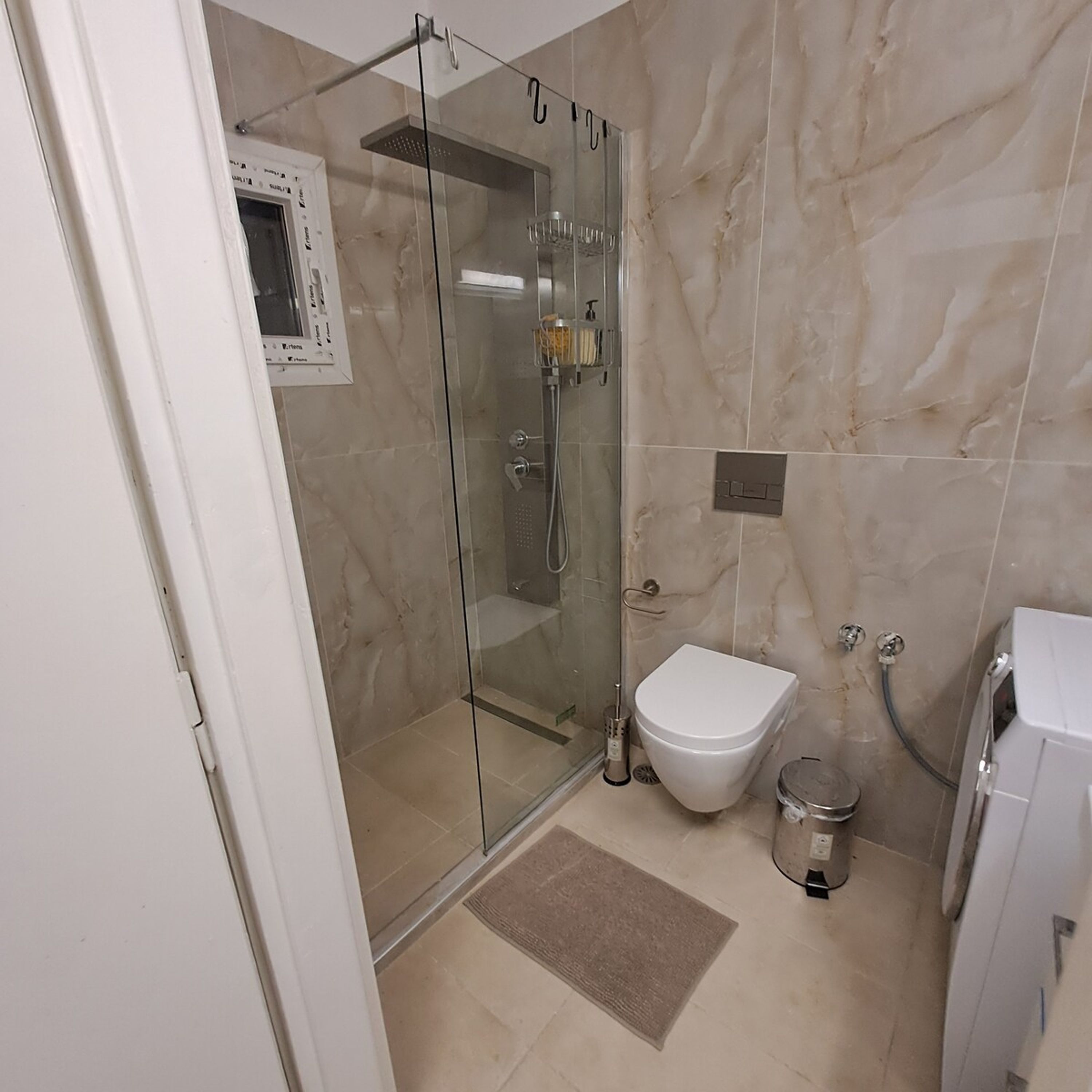 A modern bathroom with a glass-enclosed shower, a toilet, and a bidet.