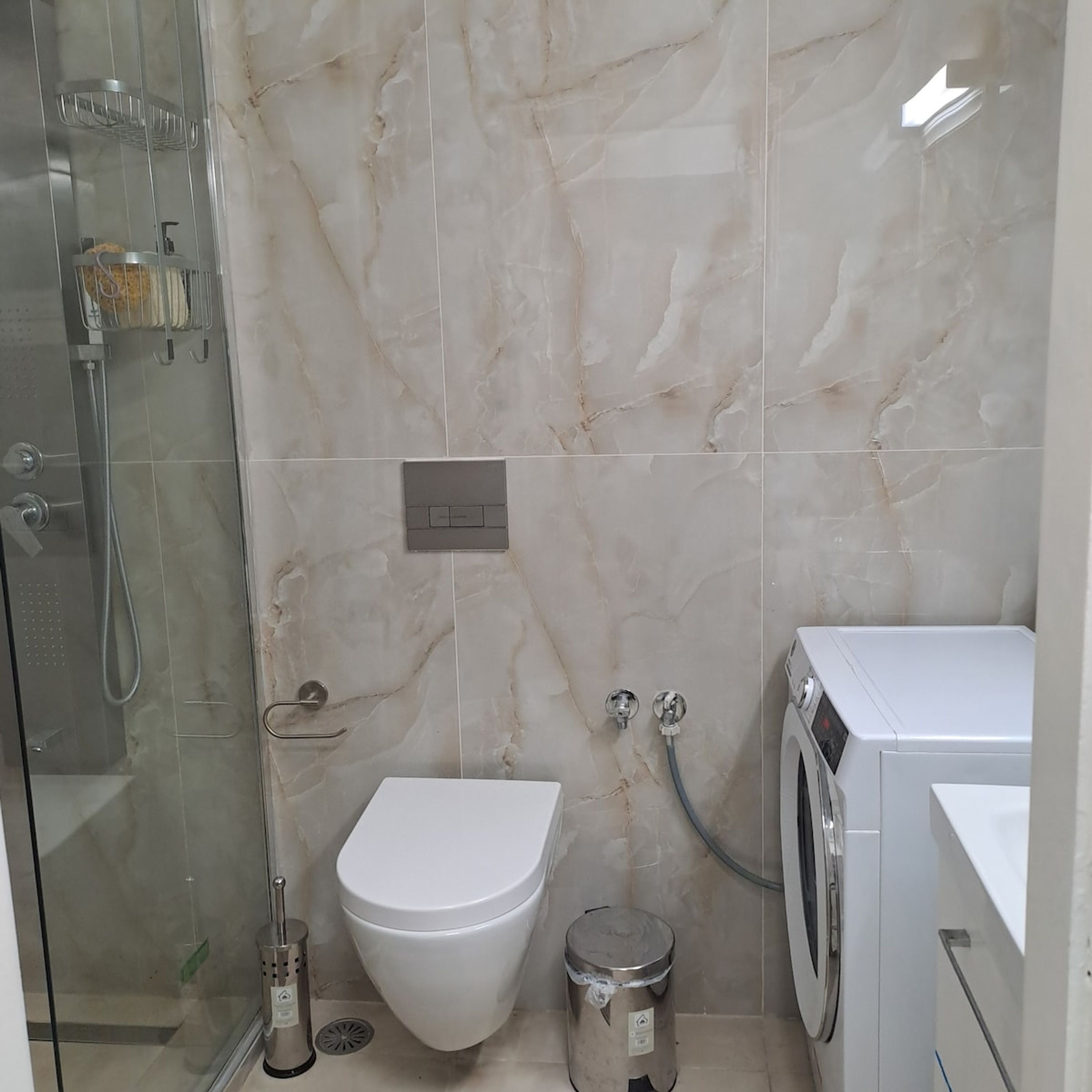 Une salle de bain équipée de toilettes, d’un bidet, d’une douche et d’un lave-linge.