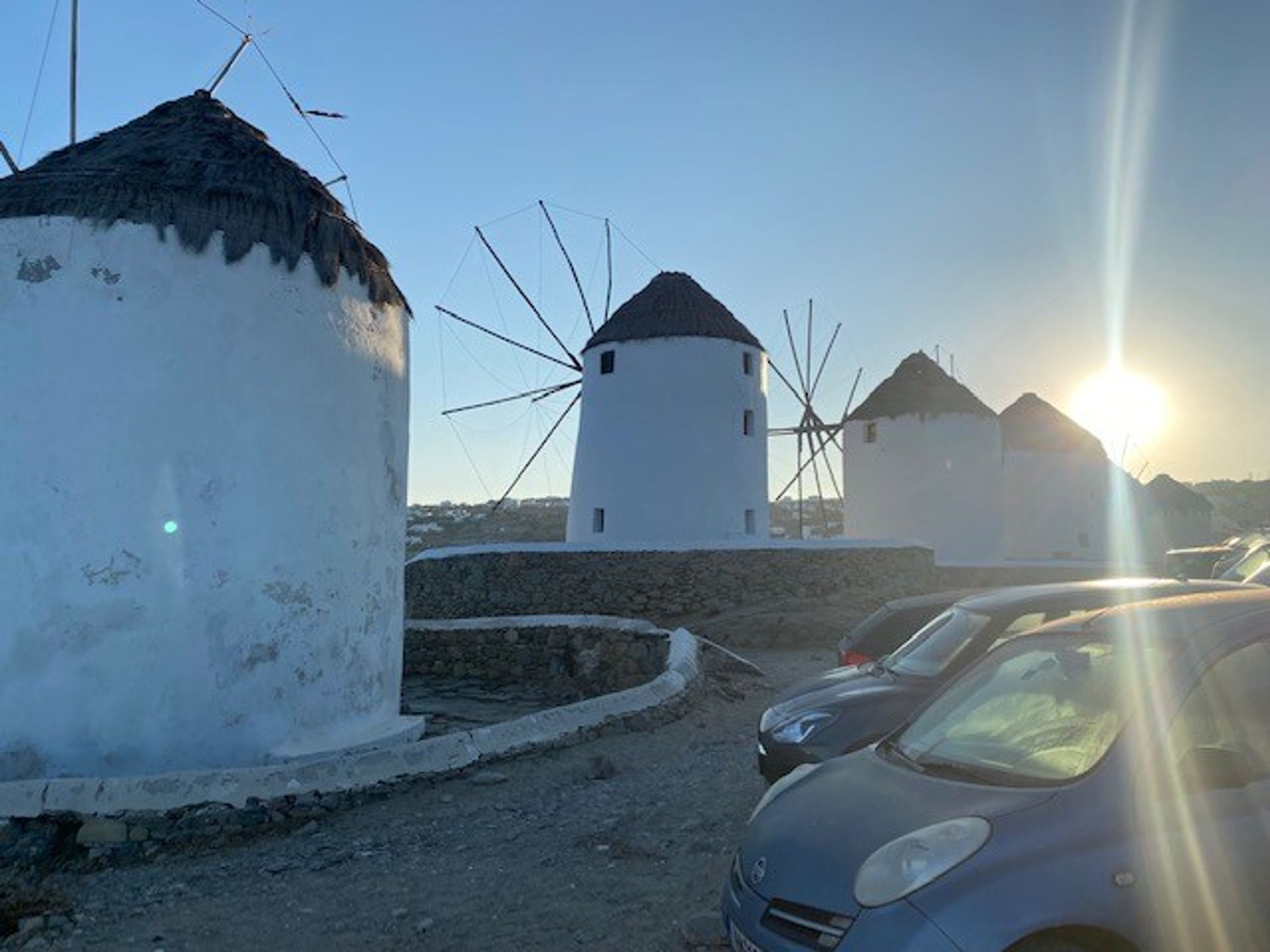 Una hilera de molinos blancos con un coche estacionado al frente.