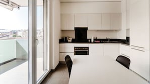 Eine moderne Küche mit weißen Schränken, einer schwarzen Arbeitsplatte und einem Essbereich mit Tisch und Stühlen.