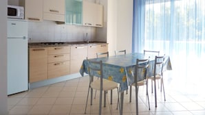 A kitchen with a dining table and chairs, a microwave, and cabinets. - Spacious Apartment With Terrace Near the Beach (San Michele al Tagliamento)