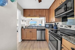A kitchen with wooden cabinets, stainless steel appliances, and a dishwasher. - Gulf Views! 2 Bedroom Townhome in Inlet Beach! (Inlet Beach)