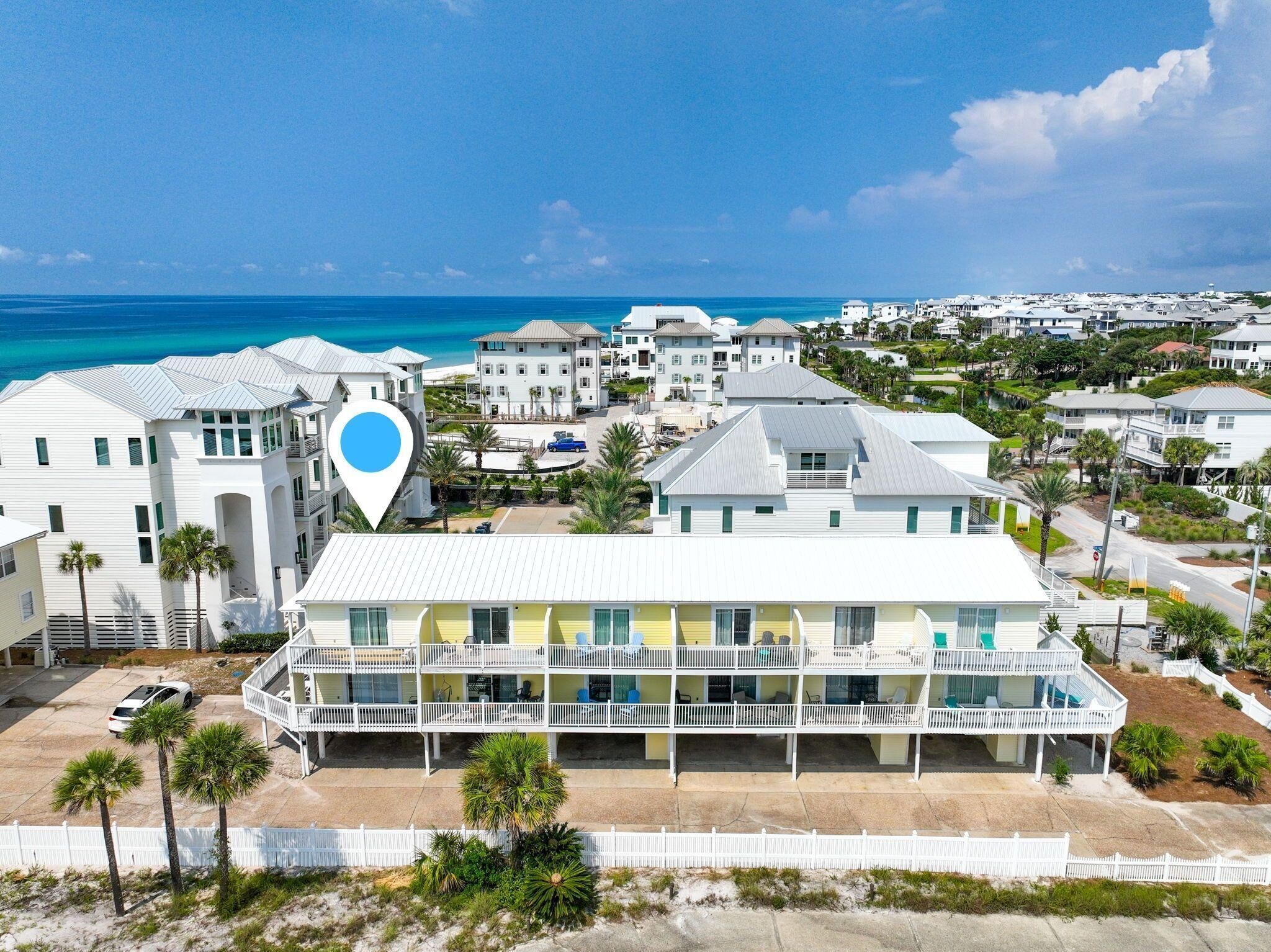 A beachfront hotel with multiple balconies, a pool area, and a view of the ocean.