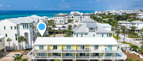 A beachfront hotel with multiple balconies, a pool area, and a view of the ocean.