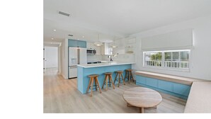 Een moderne keuken met een centraal eiland, barstoelen en een raamzitje.