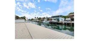 A marina with boats docked, a wooden walkway, and a building with a balcony. - Beautiful waterfront home in Islamorada, Fl Keys! Ready for only your clothes!! (Tavernier)