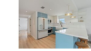 Een moderne keuken met een centraal eiland, witte kasten en een blauwe accentmuur.