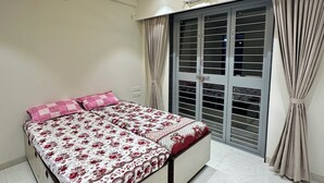 A bedroom with a bed, ceiling fan, and large windows with curtains.