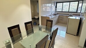 A modern kitchen with a glass dining table, built-in cabinets, and a window with a view.