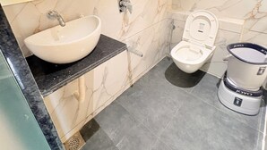 Une salle de bain avec un mur en marbre, un lavabo, des toilettes et un bidet.
