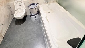 Une salle de bain avec un mur en marbre, des toilettes, un bidet et une baignoire.