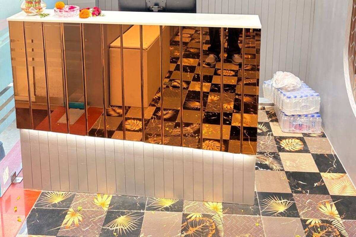 A reception desk with a laptop, a potted plant, and a checkered floor pattern.