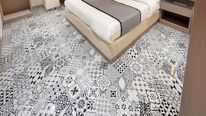 Une chambre d’hôtel moderne dotée d’un grand lit, d’un ventilateur de plafond, d’un bureau avec une chaise et d’une fenêtre avec des rideaux.
