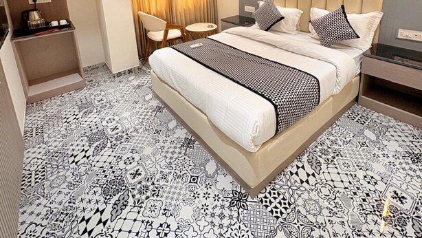 Une chambre d’hôtel moderne avec un grand lit, un ventilateur de plafond, une petite table et une fenêtre avec des rideaux.