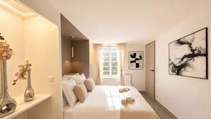 A hotel room with a bed, bedside tables, a window with curtains, a radiator, and a wall-mounted artwork. - 1532 Mouffetard (Paris)