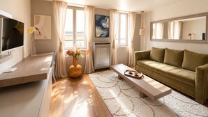 Una sala de estar moderna con un televisor de pantalla plana, un sofá, una mesa de centro y un jarrón con flores.