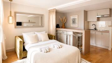 Una habitación de hotel con cama, zona de estar con sofá, kitchenette y baño.