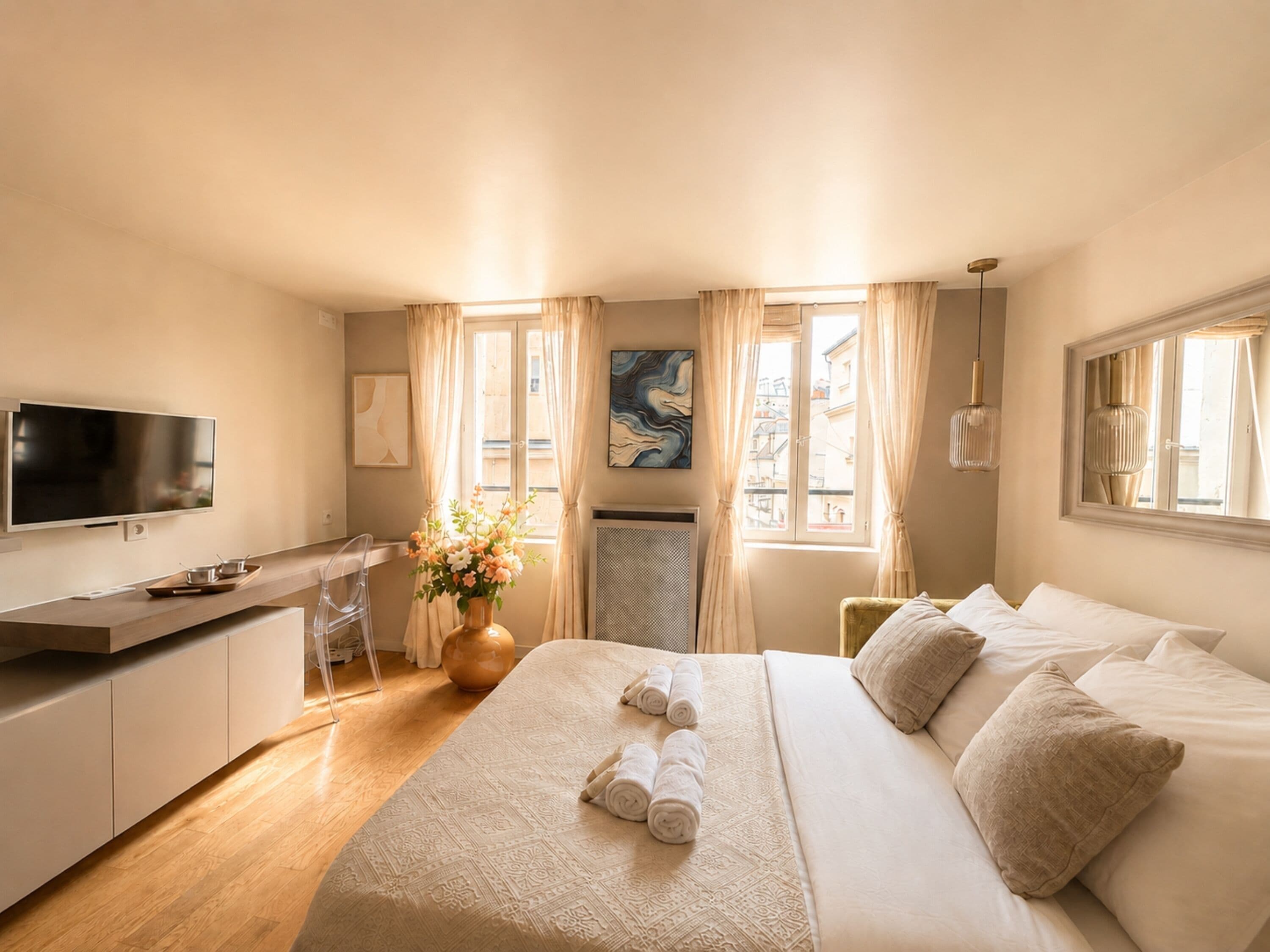 Una habitación de hotel con una cama, un escritorio, un televisor y una ventana con cortinas.