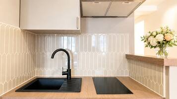 Una cocina moderna con un grifo negro, campana extractora de acero inoxidable y encimera de madera.