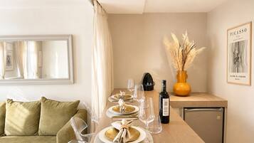 Comedor con mesa dispuesta para cuatro, una botella de vino y un florero con plumas de pluma.